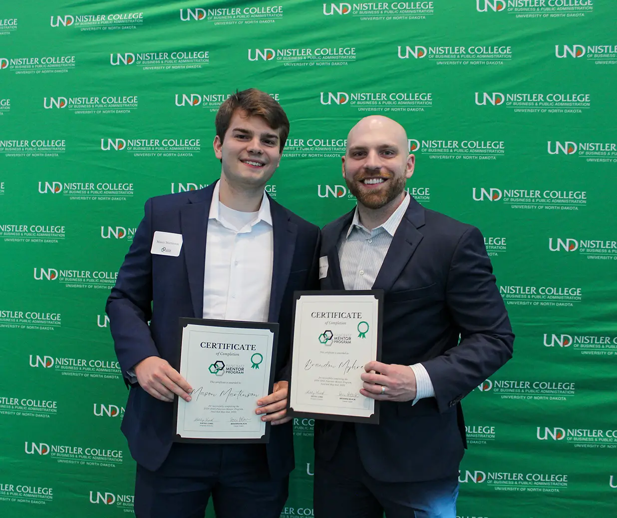 Mason and Brendon posing with completion certificates by UND background