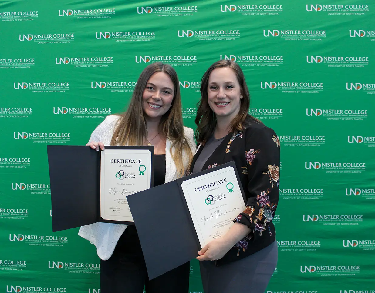 Elyn and Nicole posing with completion certificates by UND background